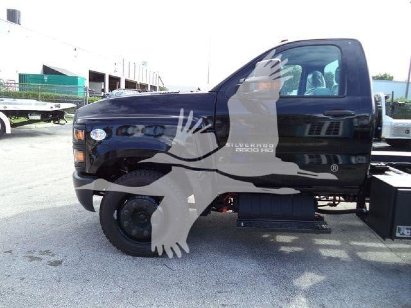 Side view of a black 2023 Chevrolet Silverado 6500HD rollback truck with logo and decals visible on the cab door.