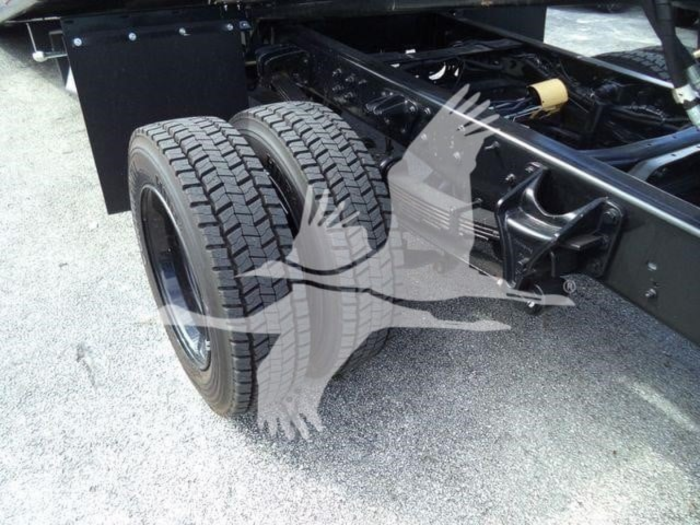 Truck rear axle and dual tires visible with chassis frame and suspension components.