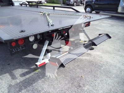 Rear view of a 2023 Chevrolet Silverado 6500Hd rollback truck showing loading ramp and flatbed with hydraulic platforms and rear taillights.
