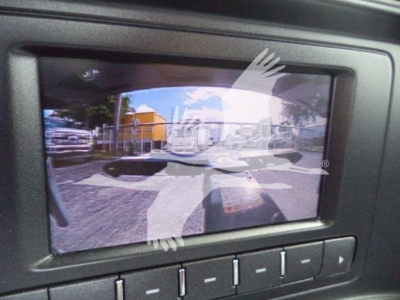 Component: backup display screen showing a camera feed with vehicles and surroundings in a parking lot.