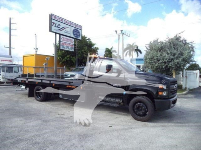 Truck with flatbed rollback showing Chevrolet Silverado 6500 HD in serviceable condition.