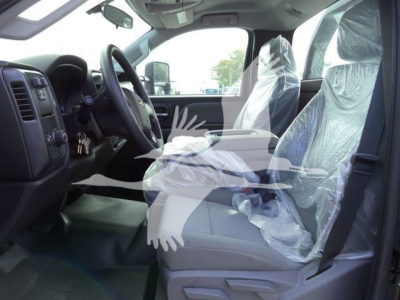Truck interior showing front seats with protective plastic covers, steering wheel, dashboard, and driver-side door.