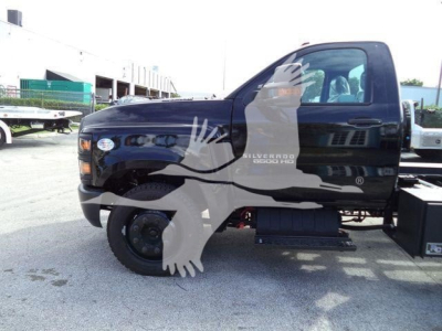 Side view of a black 2023 Chevrolet Silverado 6500HD rollback truck with logo and decals visible on the cab door.