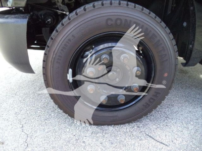 Wheel and tire of a 2023 Chevrolet Silverado 6500HD rollback truck showing Conti tire with lug nuts and brake rotor.