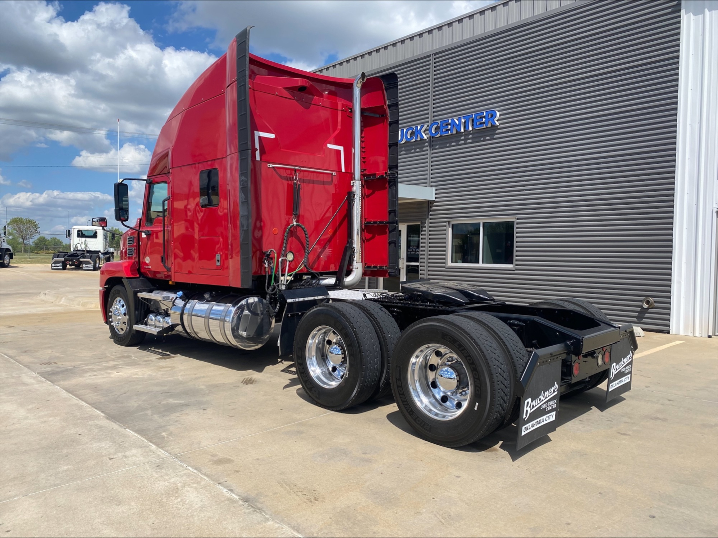 Mack AN64T70 conventional sleeper truck in red, side view showing cab and chassis with dual rear axles and chrome fuel tanks.