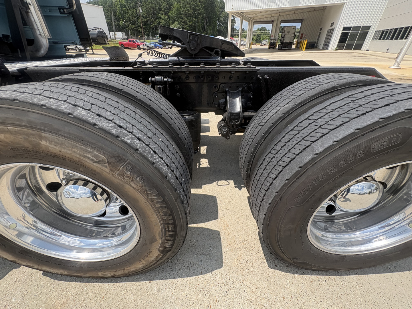 Twin rear wheels of a Volvo VNL64T760 tractor showing chrome rims and dual tires, drivetrain framing and suspension components visible between axles.