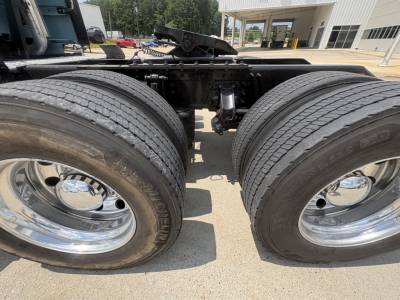 Twin rear wheels of a Volvo VNL64T760 tractor showing chrome rims and dual tires, drivetrain framing and suspension components visible between axles.