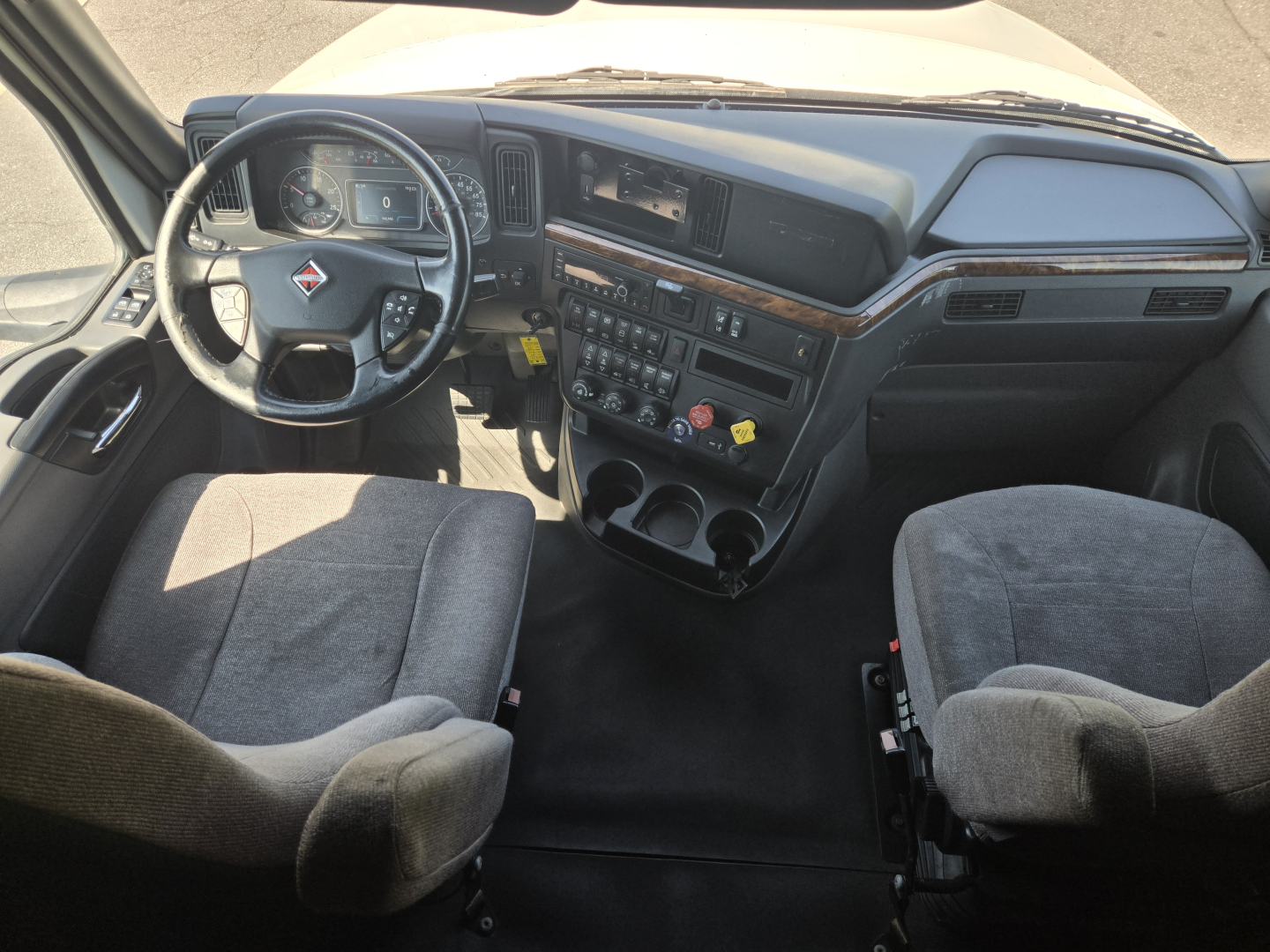 Cab interior of a 2021 International LT625 truck showing steering wheel, dashboard, center console with controls, two front seats, and a clear driver's view.