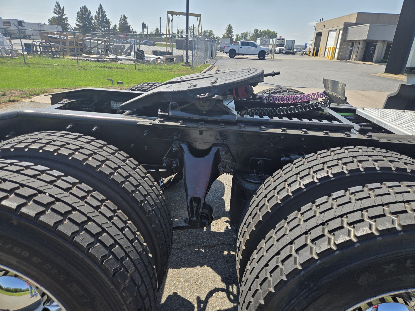 Dual rear axles of a heavy-duty truck chassis with wheels and suspension visible, middle frame view showing drivetrain and fifth wheel area, LT625 truck in background.