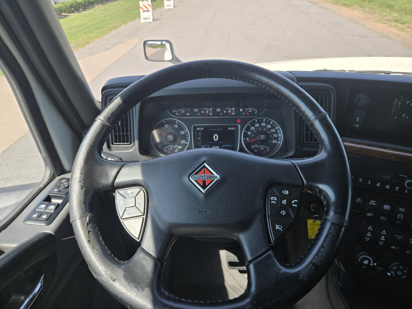 Dashboard view inside a 2021 International LT625 truck showing steering wheel with International logo and instrument cluster, plus part of center console with controls.