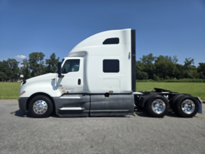 Truck side view of a white 2021 International LT625 with sleeper cab, side profile showing wheels and fuel tanks.
