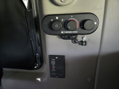 Dashboard controls with Thermo King climate control panel and a digital gauge module in a truck cab interior.