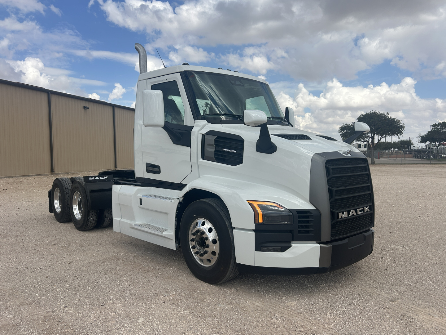 Mack PR64T conventional daycab tractor in white, side view, showing front grille with Mack emblem, dual rear axles, and chrome exhaust stack.