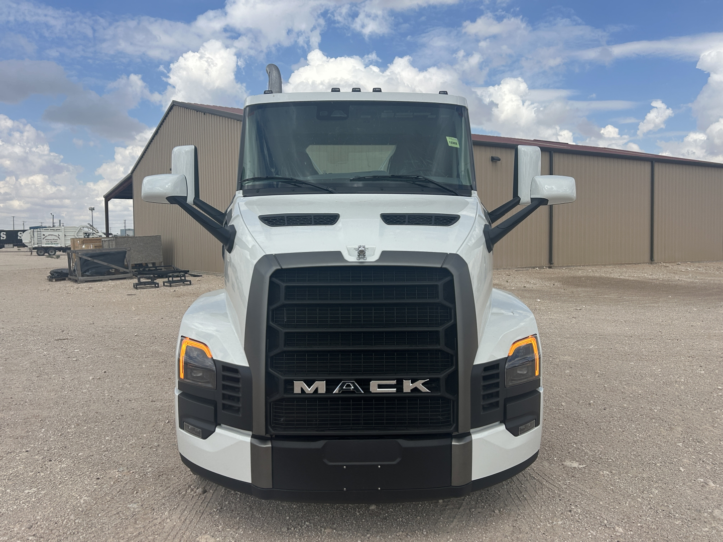 Mack PR64T front view showing large black grille, white cab, and LED daytime running lights.