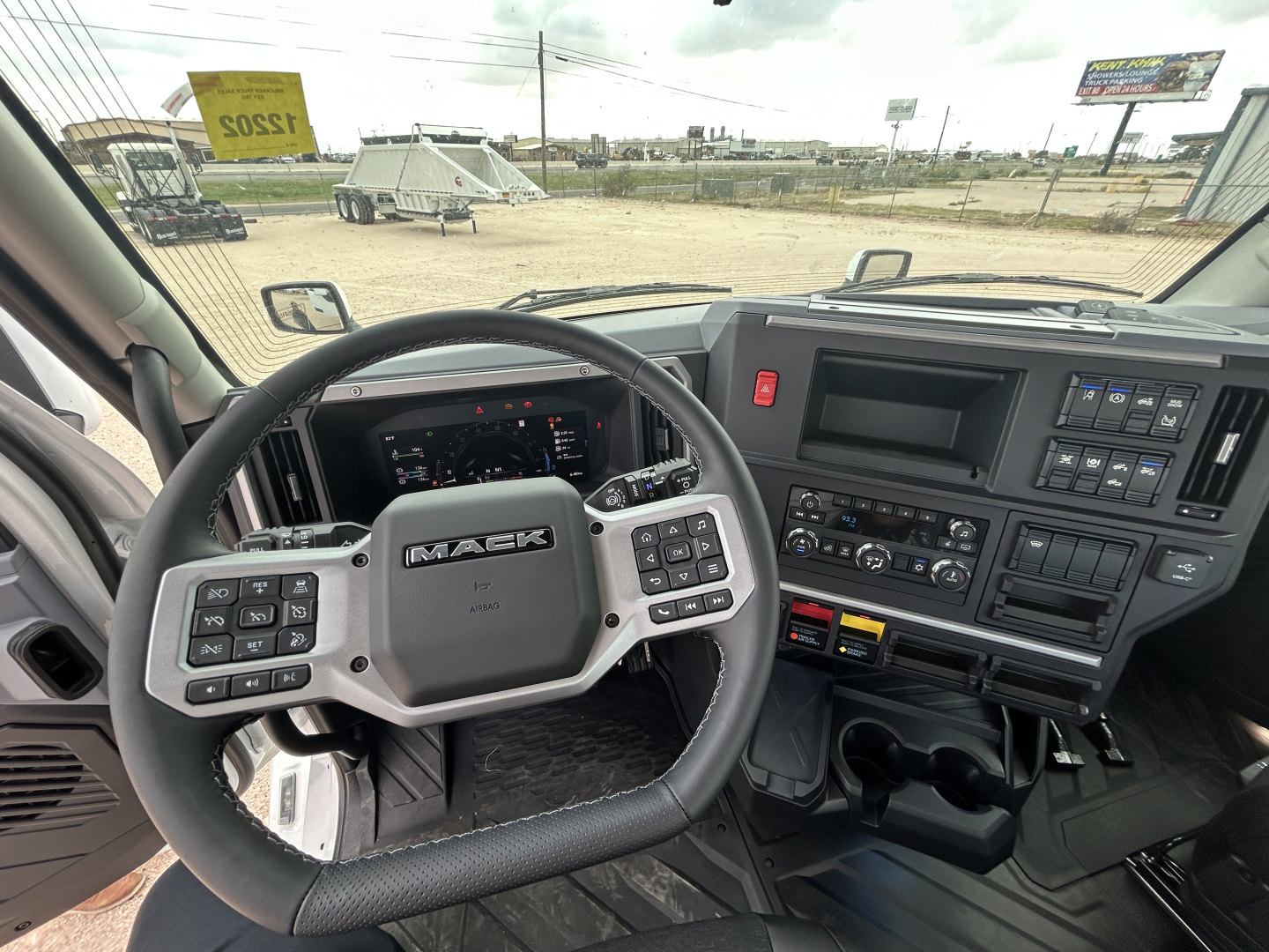 Mack PR64T truck interior showing steering wheel, dash with controls, and center console; view from driver's seat.