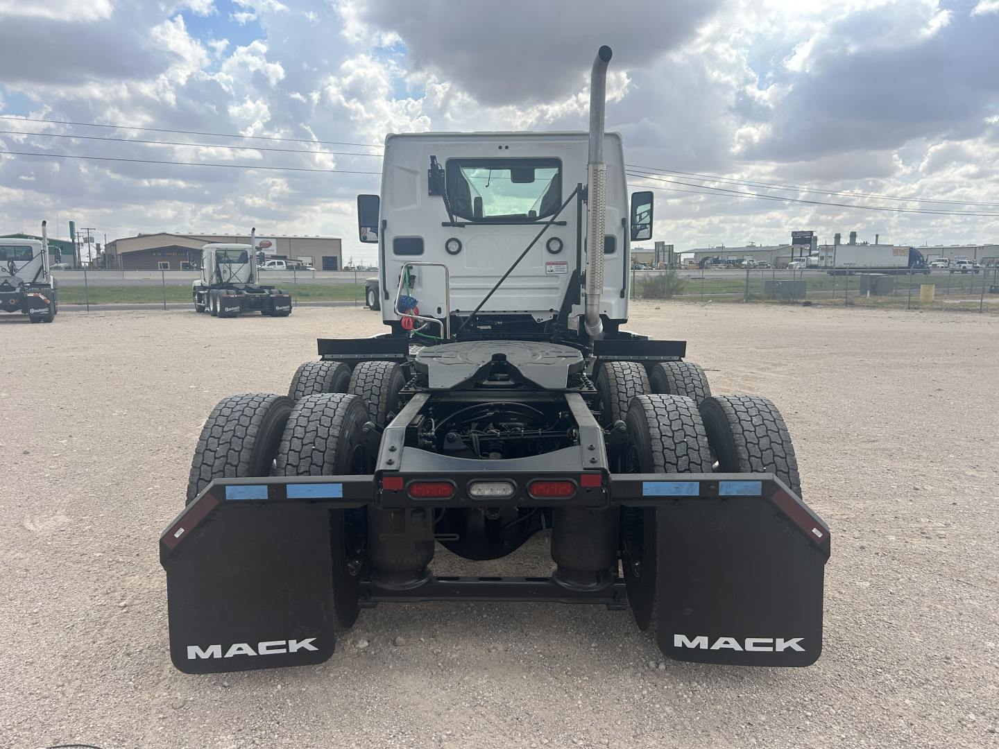 Mack PR64T truck rear view showing dual rear axles, black mud flaps with Mack logo, and chassis framing under cab.