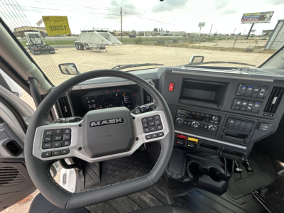 Mack PR64T truck interior showing steering wheel, dash with controls, and center console; view from driver's seat.