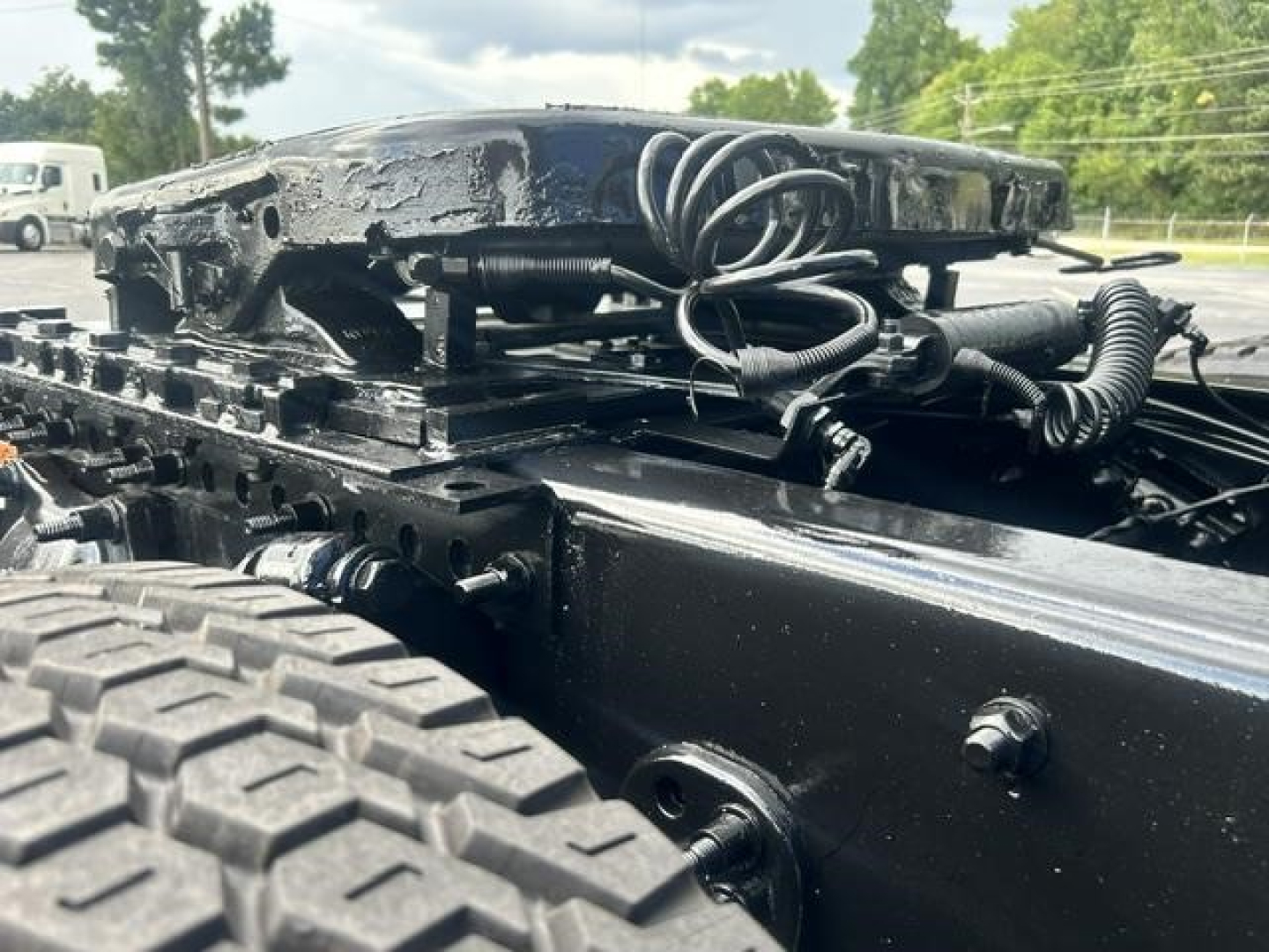 Chassis area of a Freightliner Cascadia 126 truck showing black metal frame and winch cables; part of the fifth wheel and mounting plate visible.