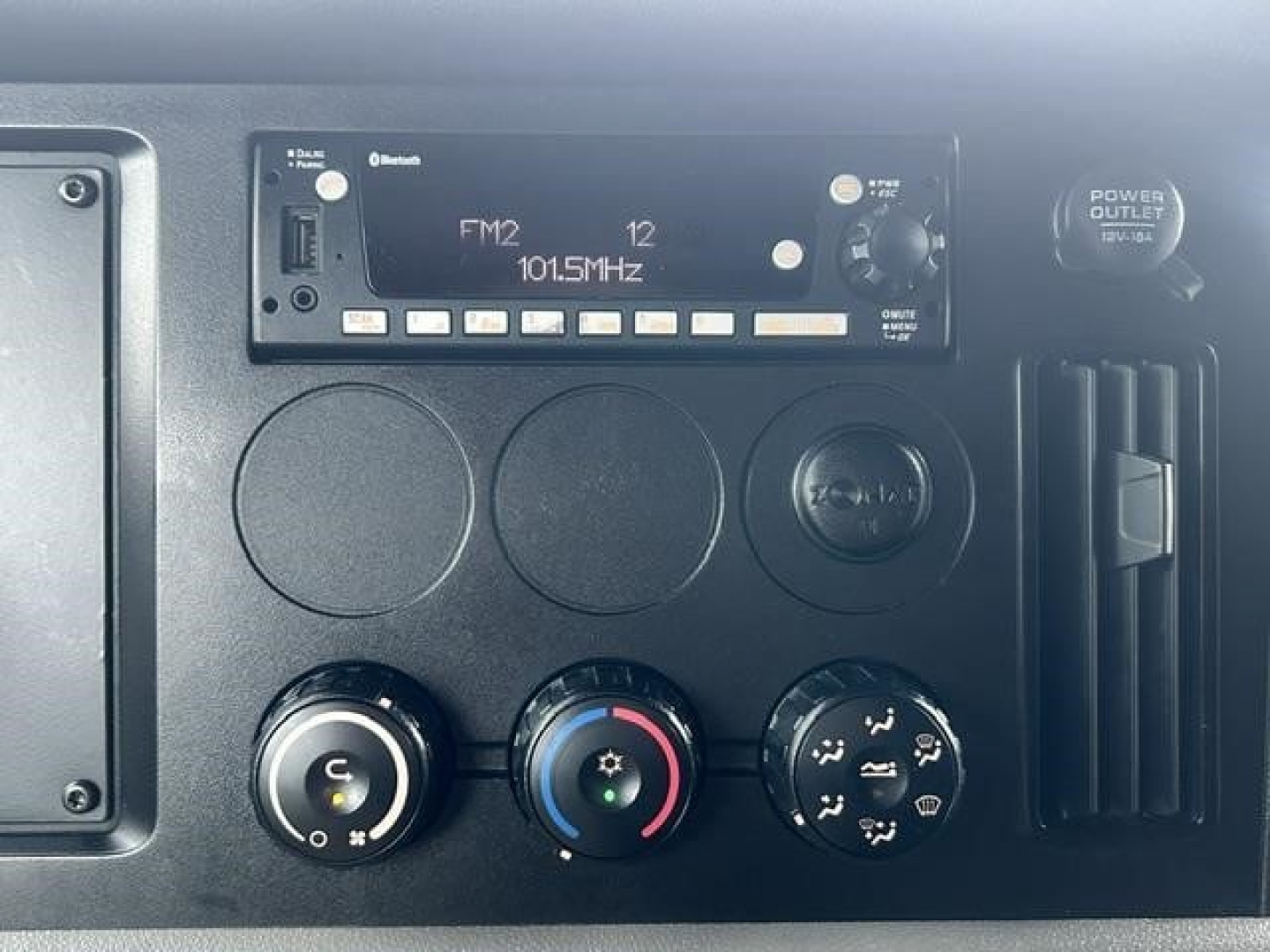 Dashboard and controls of a 2022 Freightliner Cascadia 126 sleeper cab showing radio/FM1 panel, climate knobs, and power outlet.
