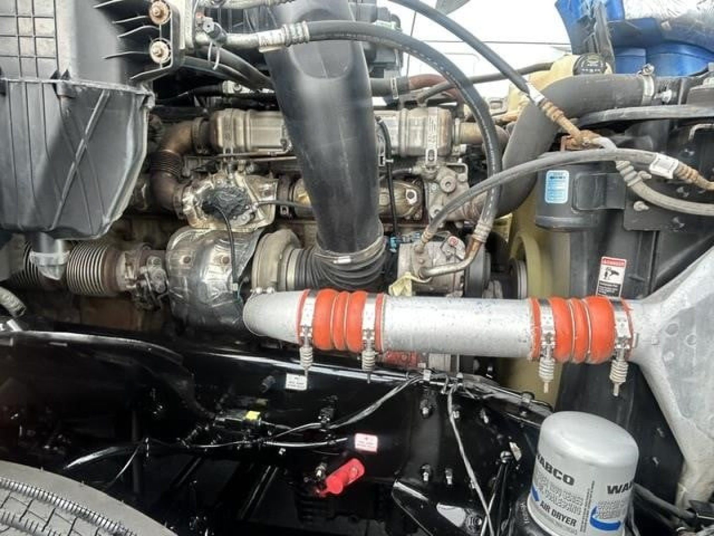 Freightliner Cascadia 126 engine bay showing turbocharger, intercooler piping, hoses, and coolant reservoir. visible components include belts, metal brackets, and wiring harnesses.