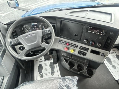 Freightliner Cascadia 126 cab interior showing steering wheel, dashboard, pedals, and central control panel.