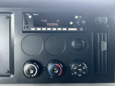 Dashboard and controls of a 2022 Freightliner Cascadia 126 sleeper cab showing radio/FM1 panel, climate knobs, and power outlet.