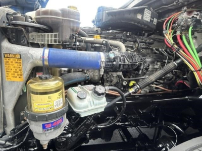 Freightliner Cascadia 126 engine bay showing blue coolant hose, yellow reservoir, and wiring harness with labels.