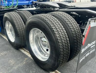 Freightliner Cascadia 126 rear dual axle with large tires and wheel rims, chassis visible.