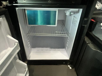 Freightliner Cascadia 126 underhood area showing empty refrigerator/freezer compartment with monitor mounted inside.