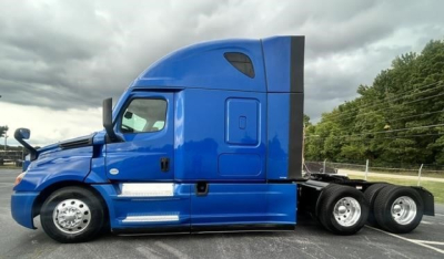 Truck cab of a blue 2022 Freightliner Cascadia 126 side view showing sleeper cab and rear wheels.