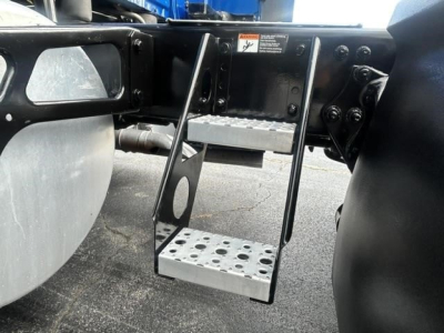 Trucker step and under-ride area of a Freightliner Cascadia 126 showing metal perforated step and surrounding chassis hardware.