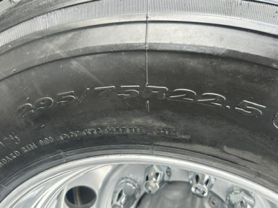 Tire close-up on a Freightliner Cascadia showing tire size 295/75R22.5 and wheel rim details.