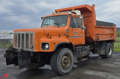 Orange 2002 International 2674 dump truck with a raised dump bed and crew cab, showing front grille, headlights, and side decals reading TOWN BRIDGEWATER.