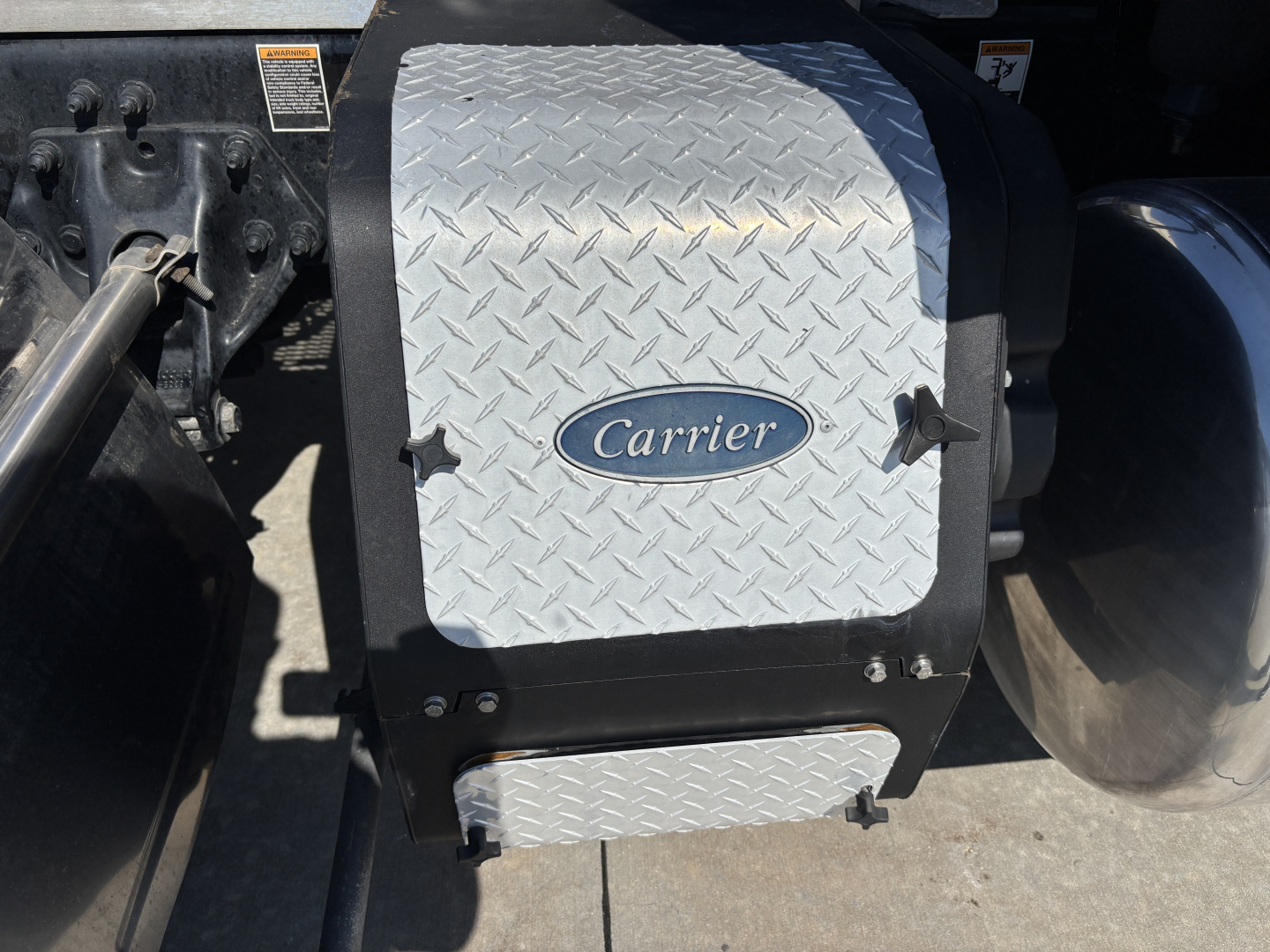 Truck engine bay area showing a diamond plate Carrier air or component cover with oval Carrier logo.”