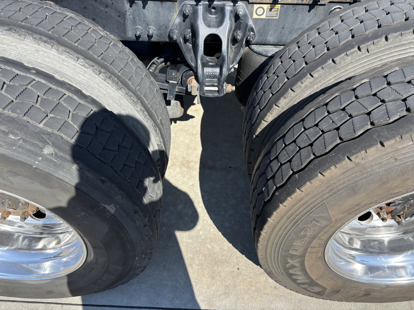 Peterbilt 389 trucks showing dual rear wheels and hitch/mounting area under PTO, with heavy tires and chrome wheels visible.