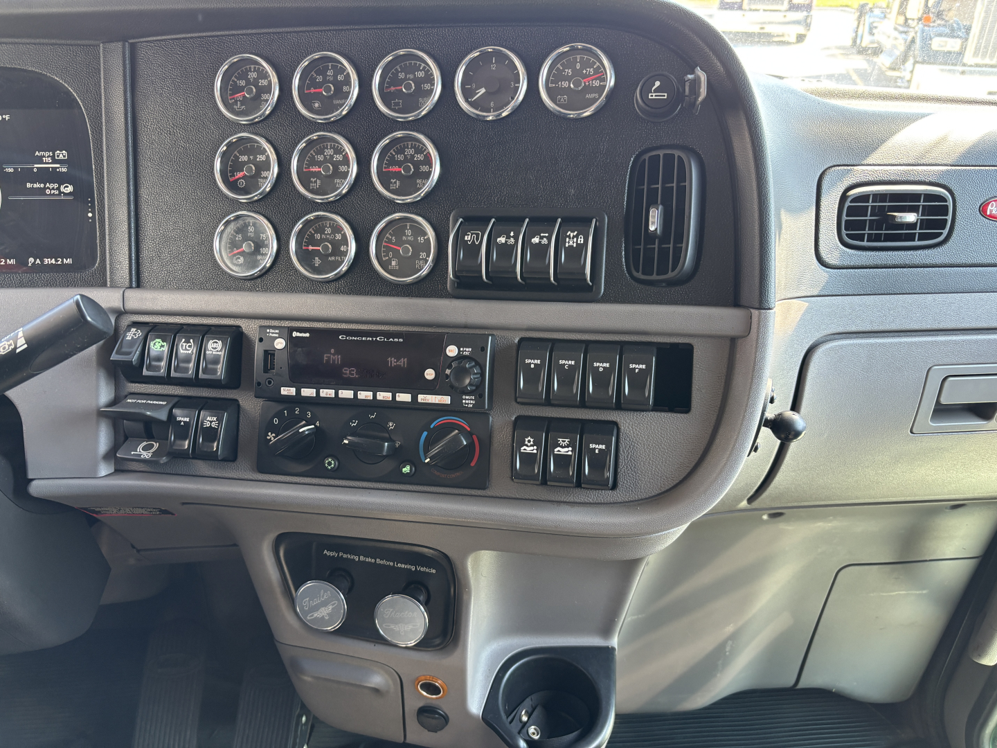 Peterbilt 389 dash and instrument cluster with multiple gauges and control switches.