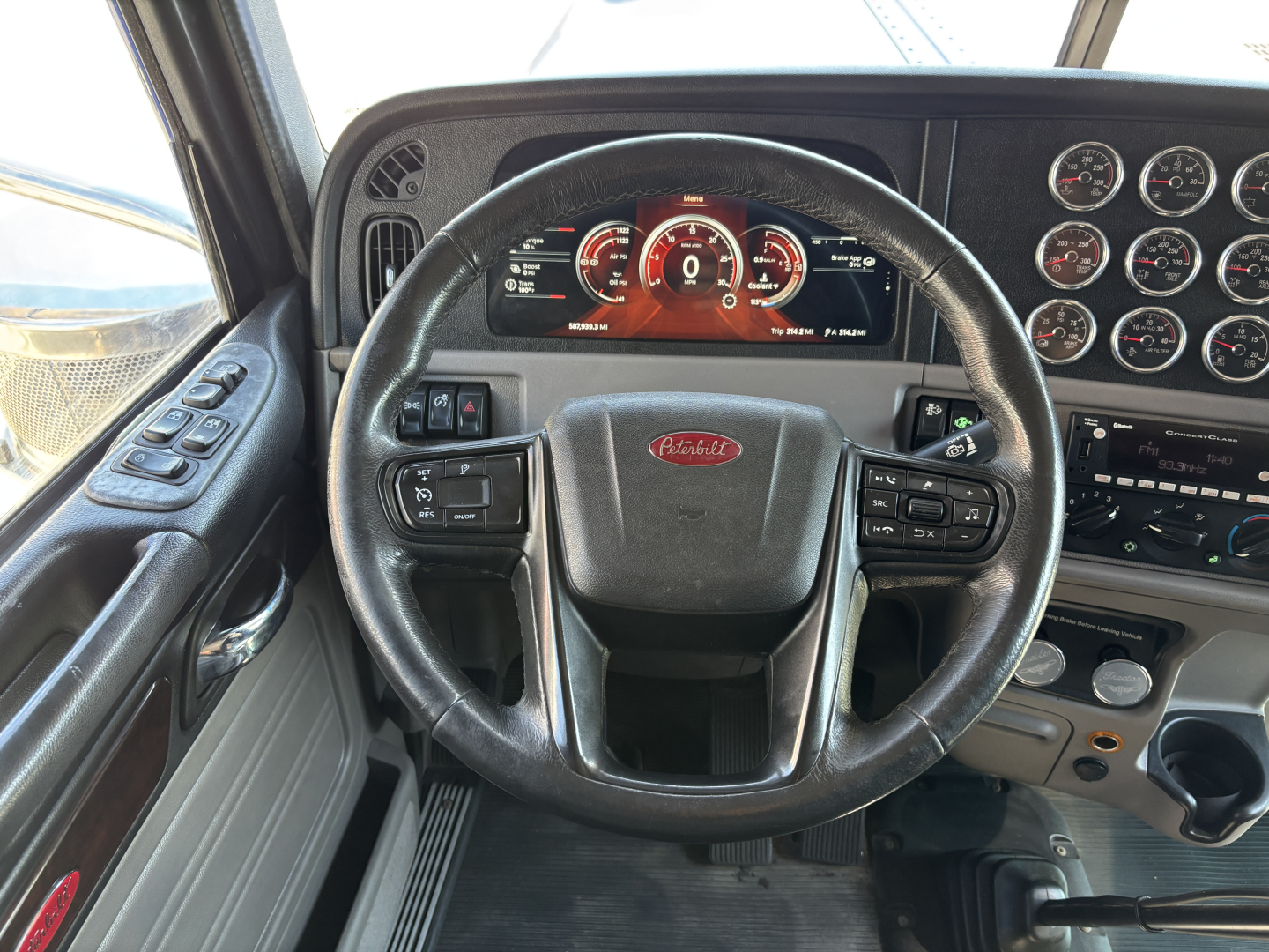 Peterbilt 389 dashboard and steering wheel view with multiple gauges and controls.