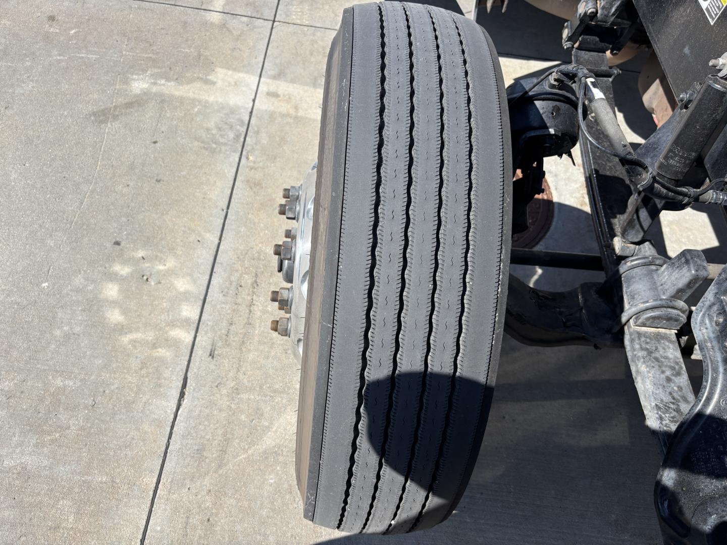 Peterbilt 389 front axle wheel showing dual rear tires and suspension components.