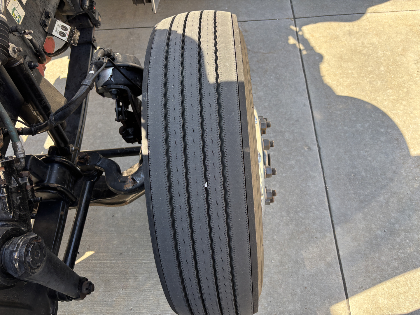 Peterbilt 389 truck front wheel and suspension showing tire with dual tread wear and wheel hub.