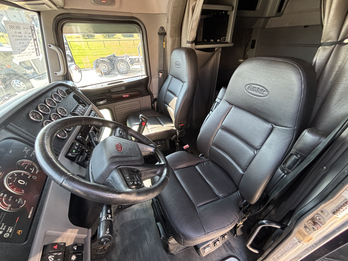 Peterbilt 389 truck cab interior showing steering wheel, dashboard instruments, and black leather seats.
