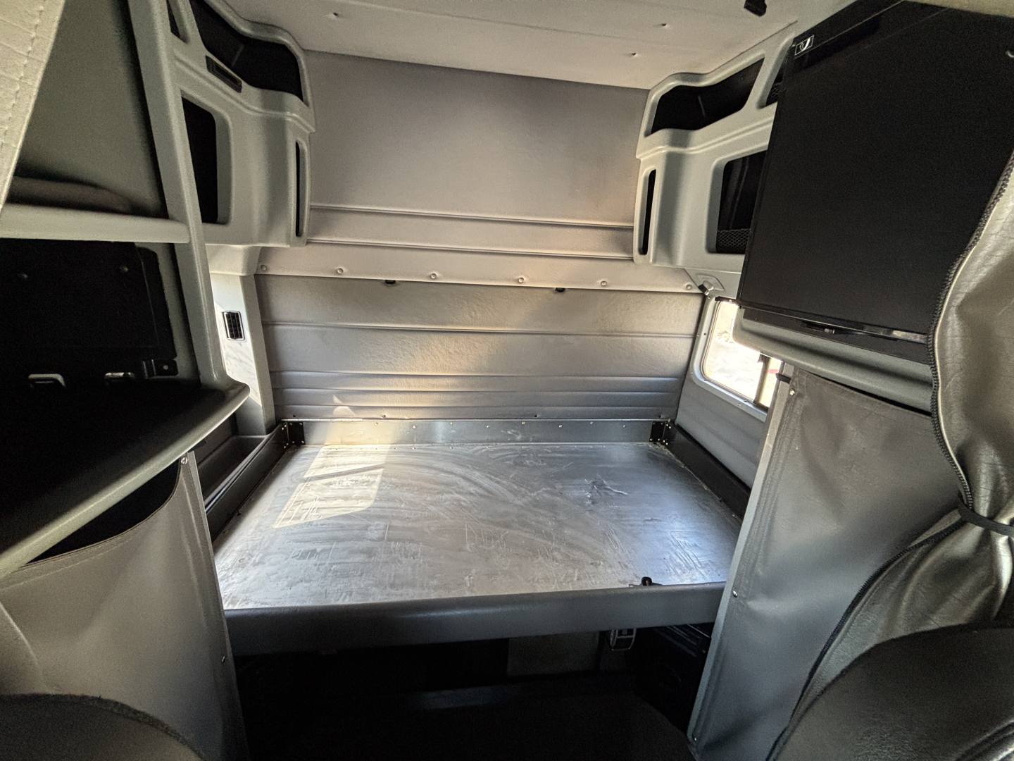 Peterbilt 389 sleeper cab interior cargo area with metal bed platform and surrounding storage compartments.