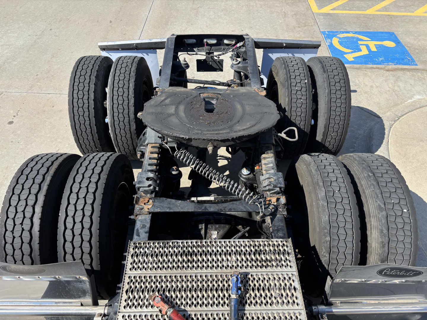 Peterbilt 389 truck chassis view showing dual rear axles with eight wheels, fifth wheel plate, and drive components.