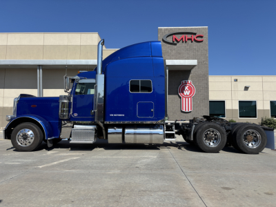Peterbilt 389 truck in blue with sleeper cab, side view showing chrome exhaust stacks and side steps, 6×4 tractor with multiple axles