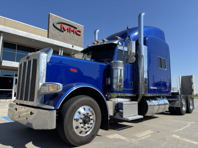 Peterbilt 389 truck in blue, side view showing cab, exhaust stacks, chrome bumper, and front grille.
