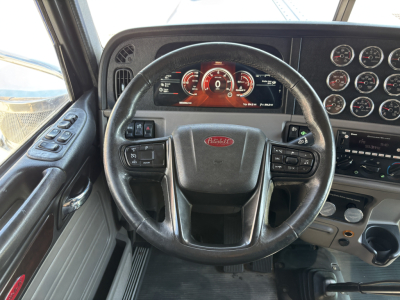 Peterbilt 389 dashboard and steering wheel view with multiple gauges and controls.