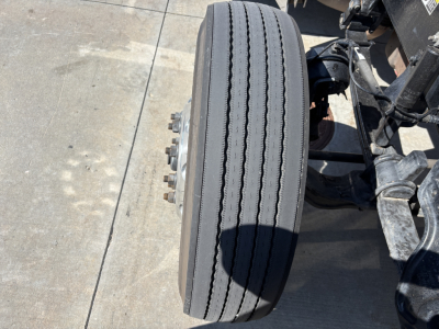 Peterbilt 389 front axle wheel showing dual rear tires and suspension components.