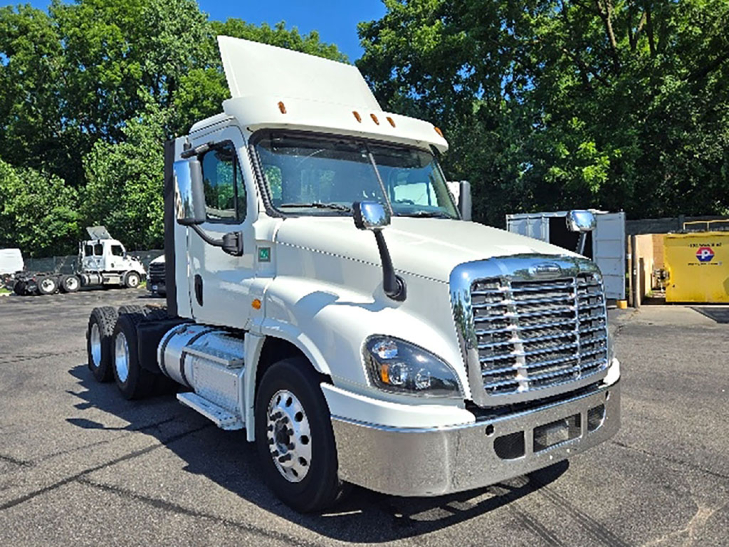 Freightliner Cascadia125 daycab truck front-left view showing upright sleeper cab, chrome grille, raised air intake, and alumni white body with large bumper.