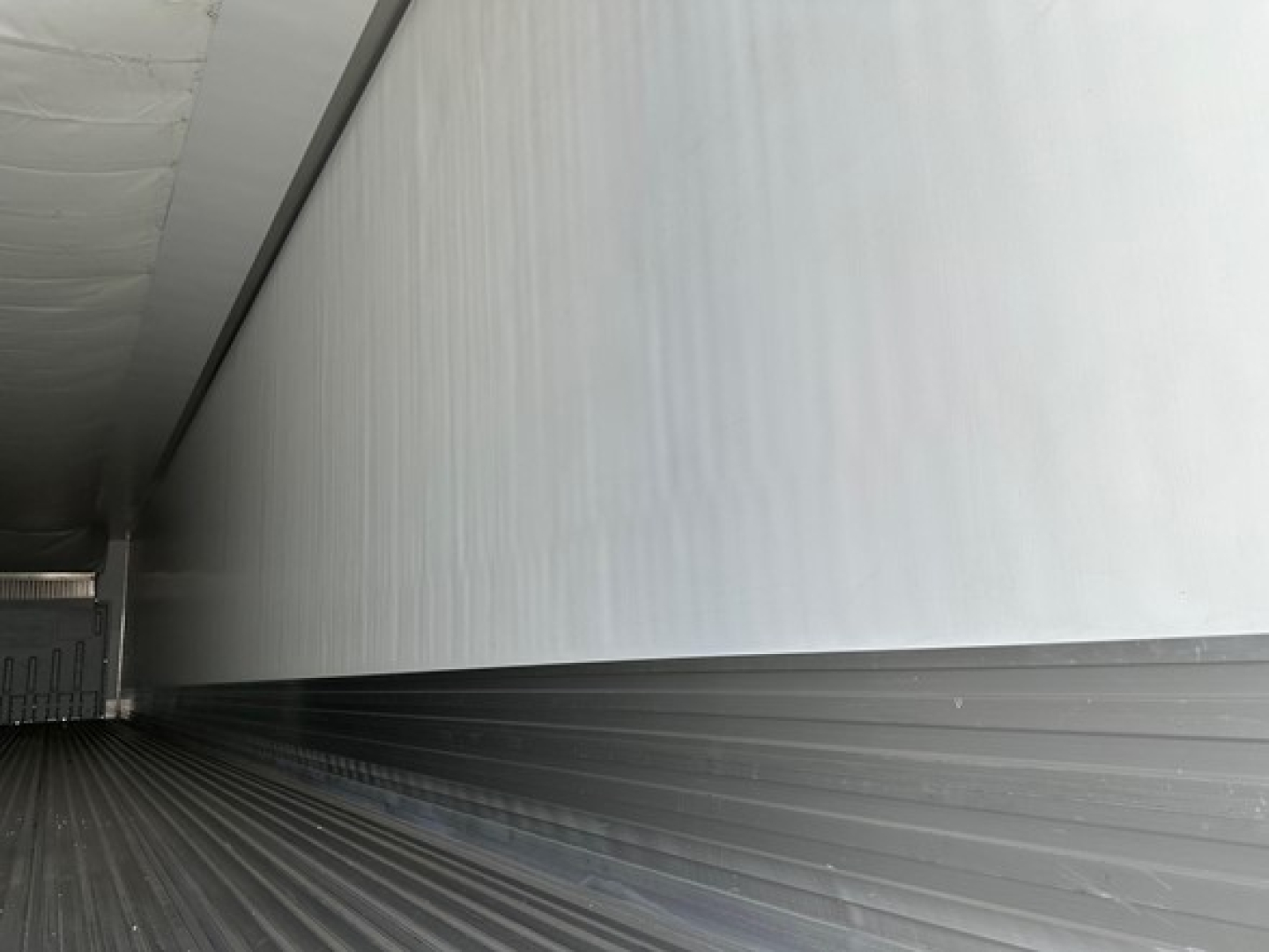 Trailer interior side wall and floor of a new Utility 3000R refrigerated trailer showing ribbed metal floor and smooth insulated wall.