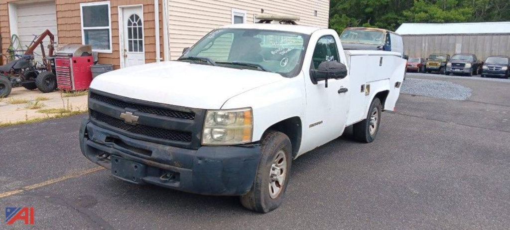 Chevrolet Silverado 1500 work truck with extended cab, white tow pickup, front bumper with plastic scuff, in a dealership lot.