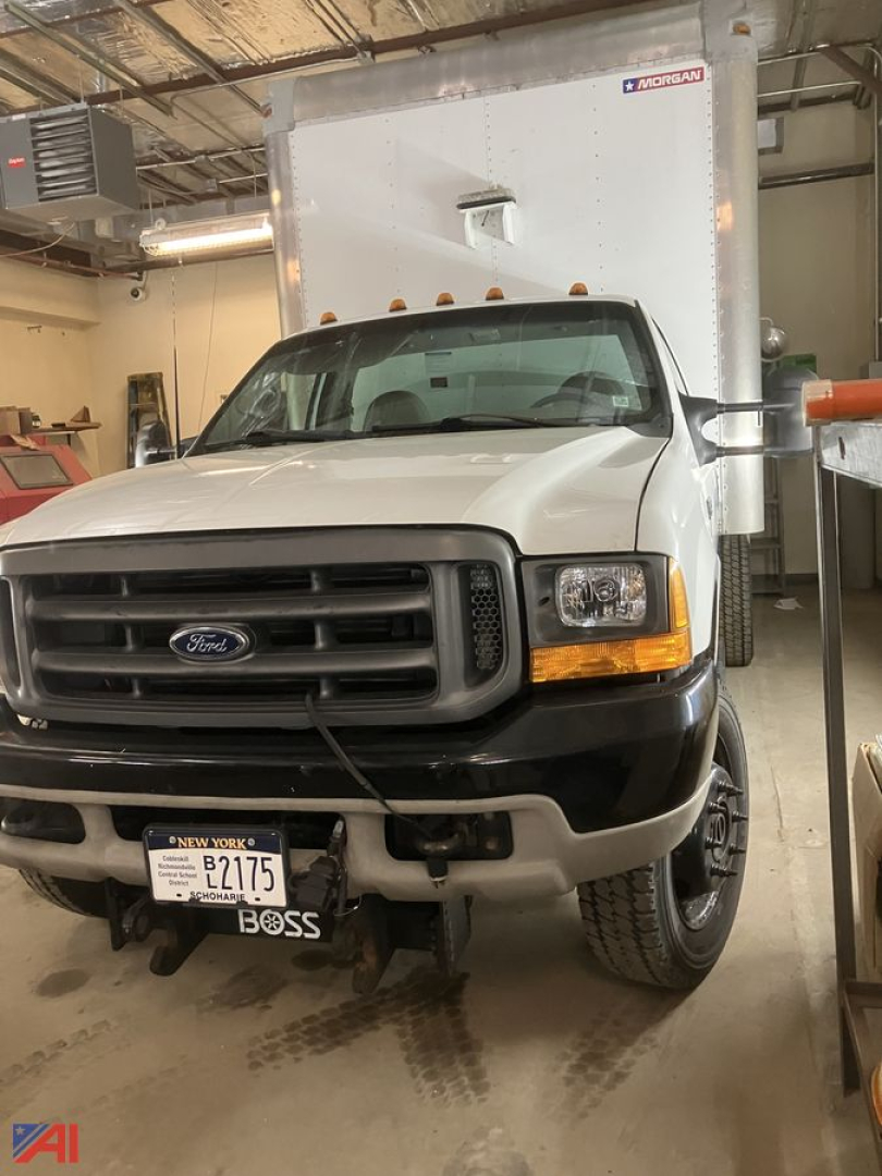 Ford F-550 truck front view with box truck in background showing grille and headlights.